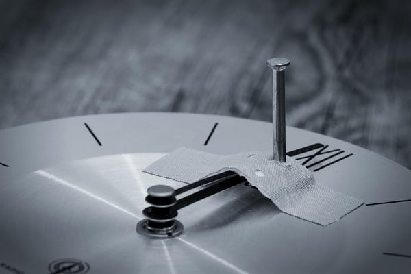 a gray dark clock has the hands spiked and taped in place.